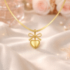 Gold bow heart pendant necklace with elegant heart charm styled on soft satin background