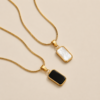 NAMIKA reversible black and white pendant necklace for women featuring a gold stainless steel two sided pendant with black and white enamel finish, anti tarnish, waterproof and hypoallergenic.