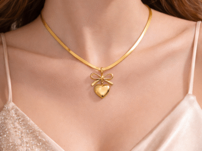 Gold bow heart pendant necklace with snake chain worn on neck with elegant feminine styling