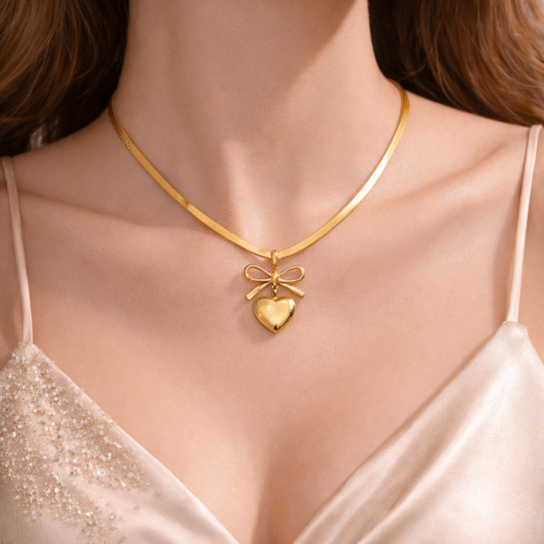 Gold bow heart pendant necklace with snake chain worn on neck with elegant feminine styling
