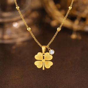 Gold clover pendant necklace with crystal accent styled on warm luxury background