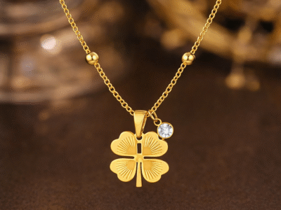 Gold clover pendant necklace with crystal accent styled on warm luxury background